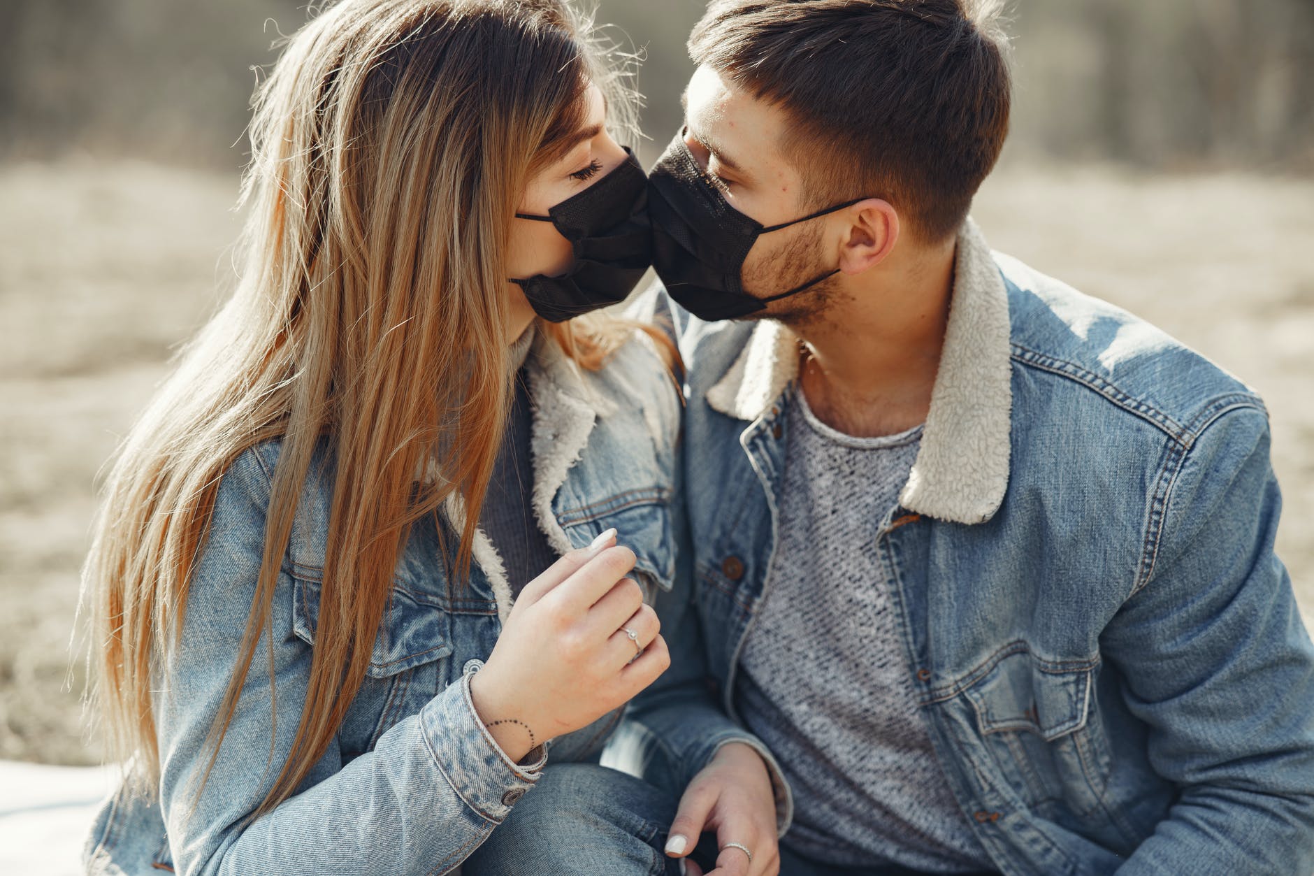 loving young couple kissing while wearing black medical masks